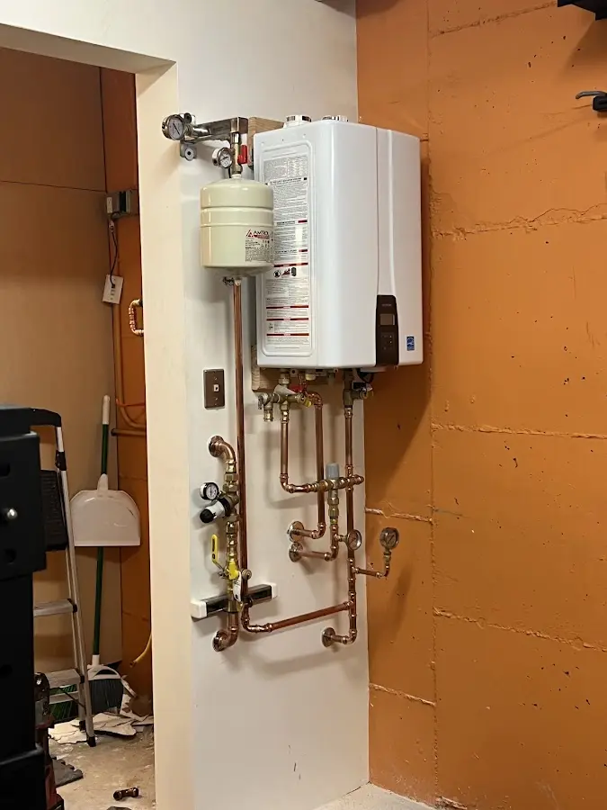 Plumbing technician inspecting water heater connections in Bethel